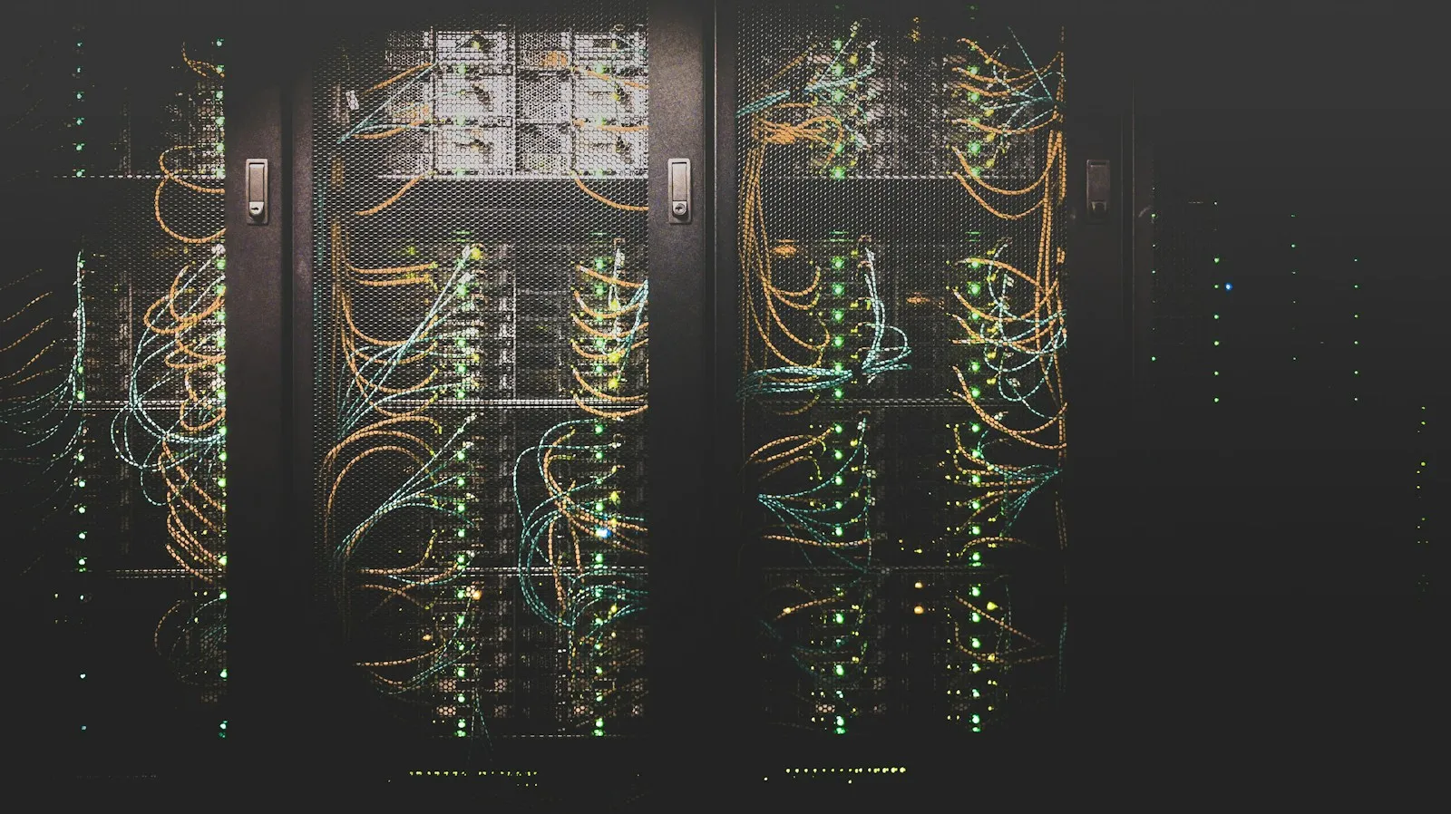 A data-centre corridor: rows of server racks with structured cabling, in low light